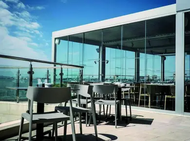cloison vitrée coulissante pour fermer une pergola qui sert de toit de terrasse d'un restaurant avec le Coulissant Panoramique Glass Systems
