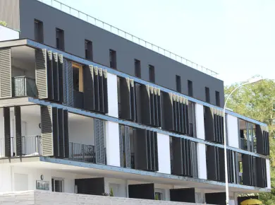 volet persienne pliant à lames mobiles de couleur anthracite installé dans une résidence privée avec plusieurs balcons.