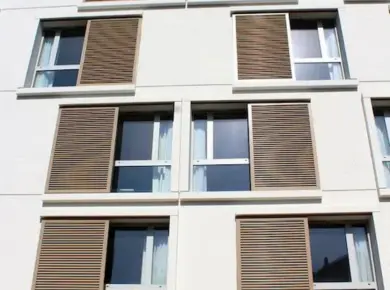 Pose en façade d'un brise-soleil comme volet coulissant avec guide en applique sur mesure en aluminium et couleur personnalisée.