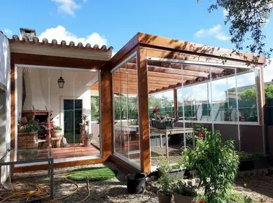 Cloison en verre intérieure et extérieure avec le Coulissant Panoramique Glass Systems pour aménager une terrasse et une pergola en bois.