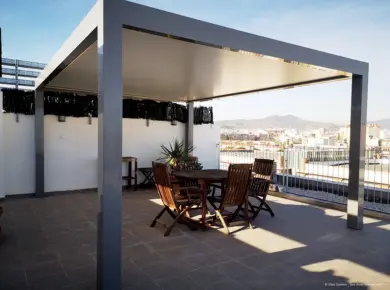 Pose d'une Pergola à Toit Plat en aluminium sur mesure sur la terrasse d'un appartement sur trouvant au dernier étage d'un bâtiment avec vue sur la ville