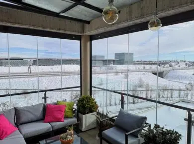 Utilisation d'un salon extérieur en hiver grâce à la pose d'un rideau de verre ou mur de verre sur mesure