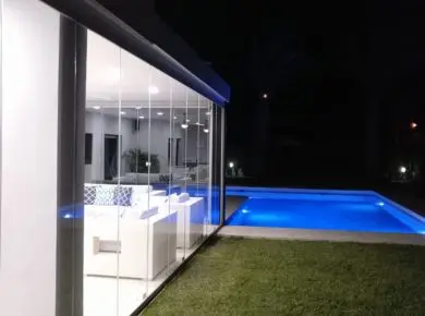 Poolhouse de nuit exploitable grâce à la solution de fermeture en verre, le rideau de verre Glass Systems