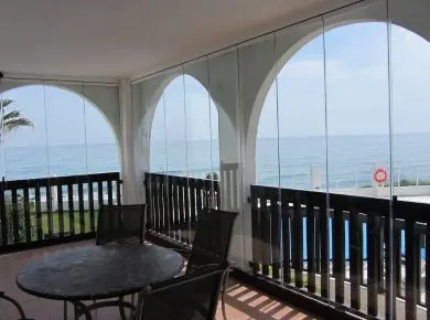 Vue intérieure d'une terrasse fermée en arche avec un système de cloison en verre extérieure de type Rideau de Verre