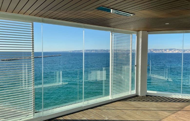 Verre panoramique installé pour fermer une terrasse donnant sur la mer et se protéger des éléments : pluie, vent, soleil
