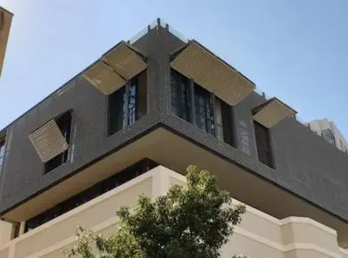 Brise-soleil horizontal installé comme volet papillon sur immeuble moderne et se confondant avec le bardage de l'immeuble en aluminium et bois thermodur