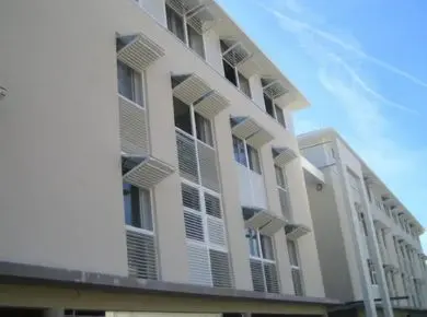 Résidence immobilière ayant opté pour des volets papillons avec une partie fixe en bas et brise-soleil relevable en aluminium blanc