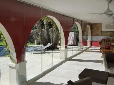 Cloison en verre intérieur extérieur avec le Coulissant Panoramique posé sur une terrasse avec des arches.