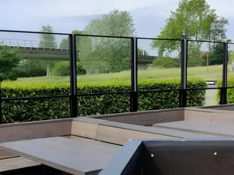 paravent extérieur noir en mode baissé avec fixation linéaire au sol sur la terrasse d'un lieu public