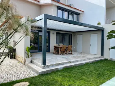 La Pergola bioclimatique autoportée sur mesure et couleur personnalisée bleu pétrole pour couvrir et abriter une terrasse de jardin.