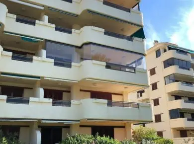 Vue extérieure d'une façade d'immeuble ayant fermé une terrasse balcon présentant des courbes, des arrondis et des lignes droites avec un Rideau de Verre Glass Systems