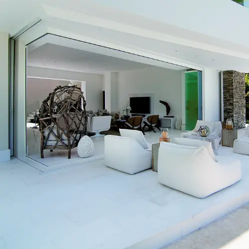 Salon d'été d'une terrasse couverte fermé par un rideau ou un mur de verre coulissant et pivotant Glass Systems